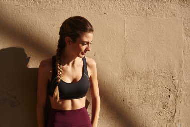 Genç bir kadın dışarıya bakıyor ve duvara yaslanıyor.