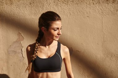 Siyah kolsuz bir bluz giyen, başını yana çevirmiş genç bir kadının yakın görüntüsü.