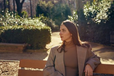Samimi bir bayan bankta dinlenirken bir yandan da bankın arkasında dinleniyor ve uzaklığın derinliklerine bakıyor.