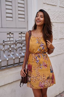 Mutlu bayan ileriye bakıyor ve çantasını tutarken bacak bacak üstüne atıyor.