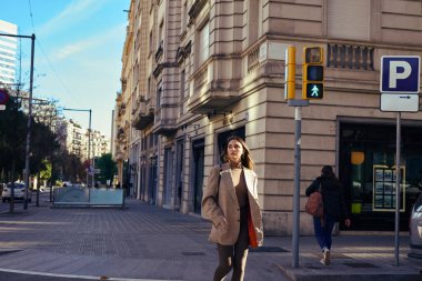 Çevresini kontrol ederken karşıdan karşıya geçmek için bekleyen yansıtıcı bir kadın.