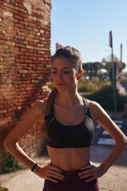 Genç, siyah saçlı bir kadının, elleri kalçasında dikilirken yaklaş.