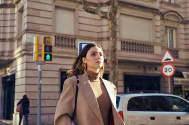 Sert kadın caddeyi geçiyor ve önüne bakıyor saçlarında rüzgarla