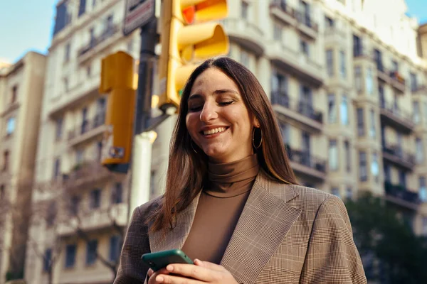 Elated Senhora Rua Sorrindo Enquanto Mensagens Texto Com Edifício Semáforo — Fotografia de Stock
