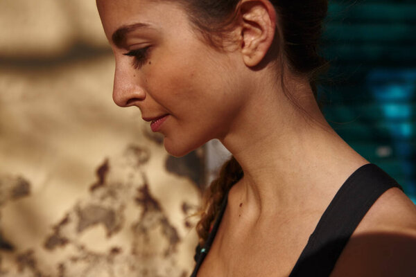 Крупный план темноволосой молодой девушки, смотрящей вниз и вдали от камеры, когда она стоит на городской улице