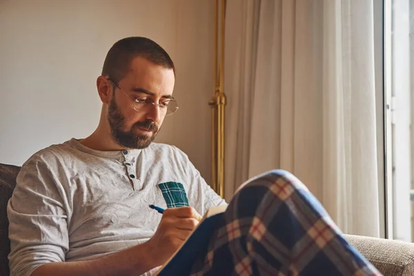 Engrossed Man Sitting Comfortably Writing Using His Lap Table — Stock Photo, Image