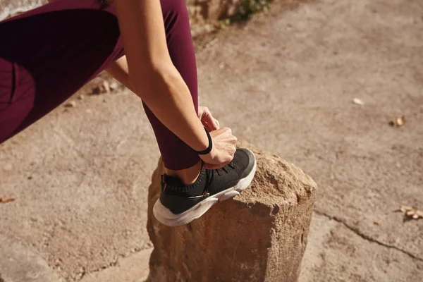 Mujer Joven Levanta Pierna Sobre Una Piedra Inclina Para Atar — Foto de Stock