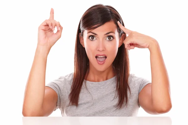 Friendly girl pointing up and to her head — Stock Photo, Image