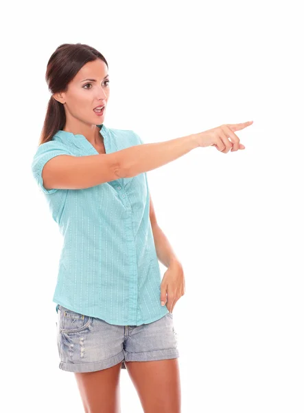 Single woman in short jeans pointing to her left — Stock Photo, Image