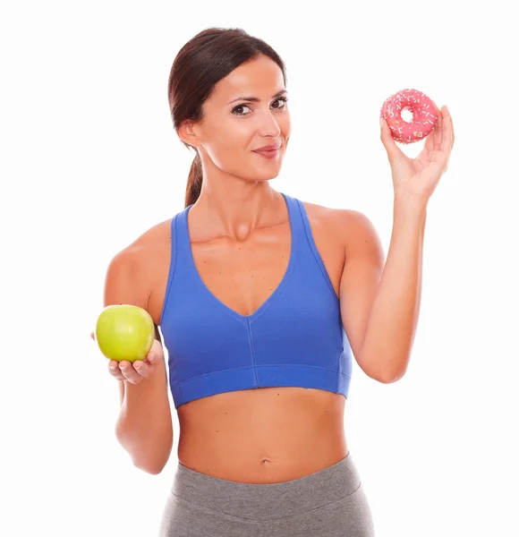 Sporty woman holding apple and donut — Stock Photo, Image