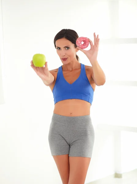 Fit female choosing between fruit and donut — Stock Photo, Image