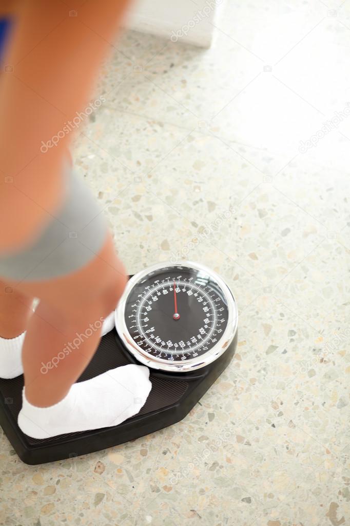 Fit pretty girl weighing herself in a scale