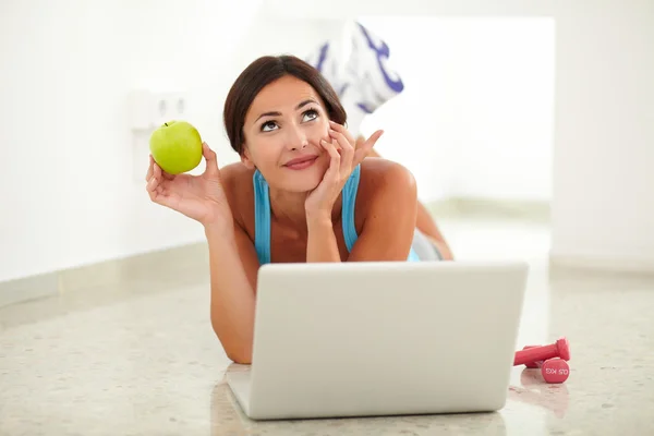Fit woman holding apple while wondering — Stock Photo, Image