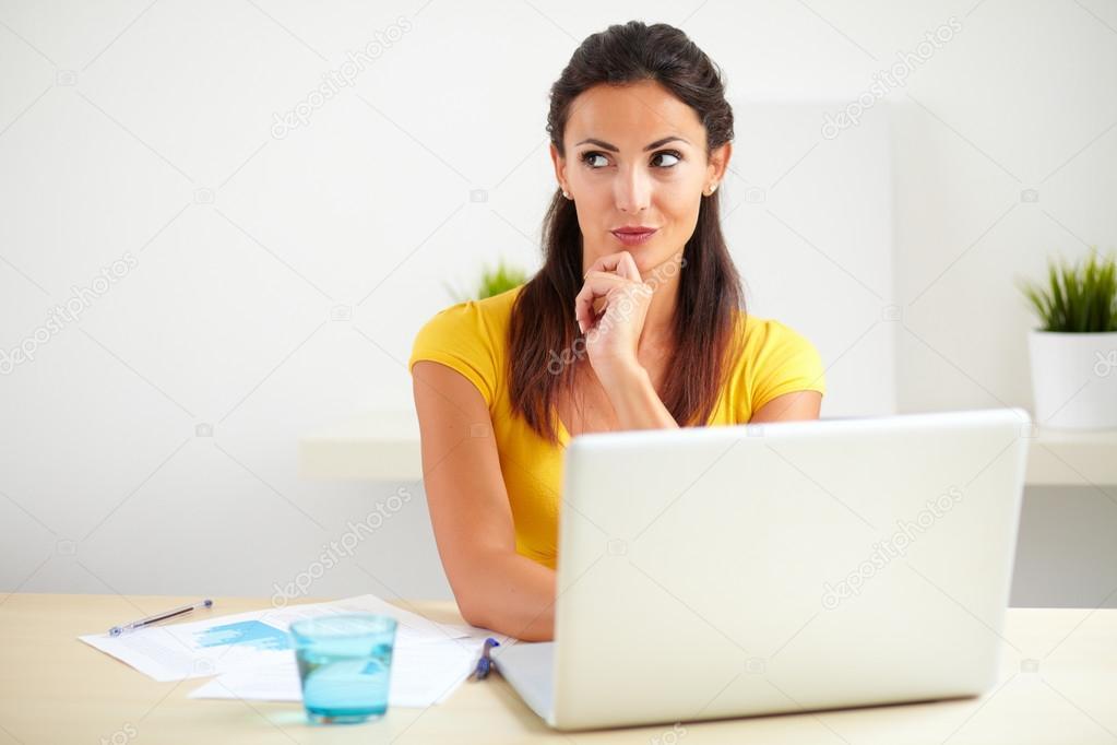 Pensive hispanic employee working on her laptop