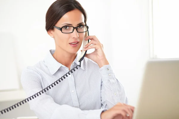 Jolie réceptionniste utilisant le téléphone sur le lieu de travail — Photo