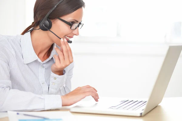 Fröhliche Empfangsdame unterhält sich auf ihrem Headset — Stockfoto