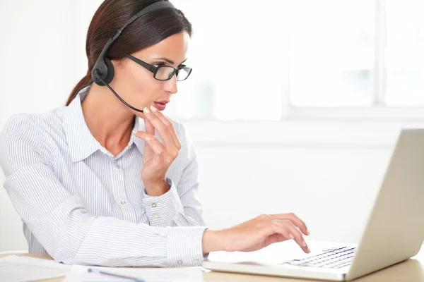 Hispanic secretaris gesprek op haar koptelefoon — Stockfoto