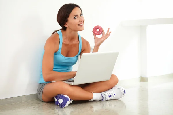 Fit female holding food and using her computer — Stock Photo, Image