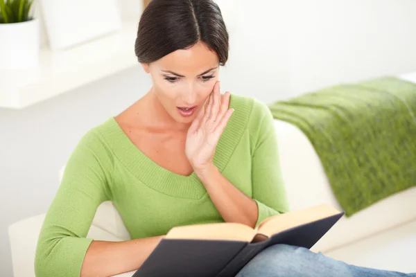 Schockierte junge Frau liest ein Buch — Stockfoto