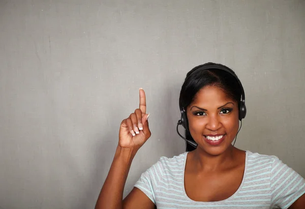 Jovem recepcionista apontando para cima enquanto sorri — Fotografia de Stock