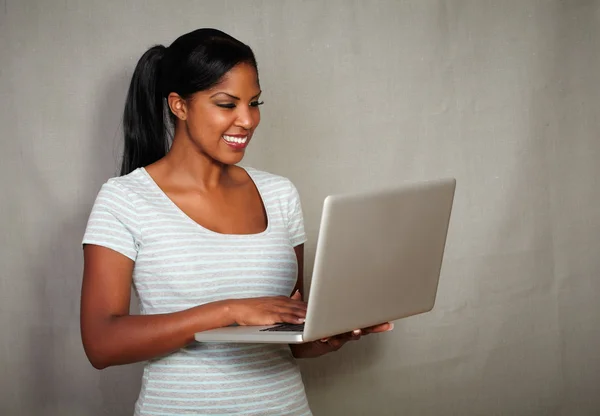 Jovem menina africana usando um laptop enquanto sorri — Fotografia de Stock