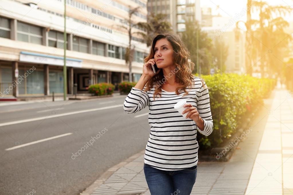 Young woman holding a coffee cup while walking