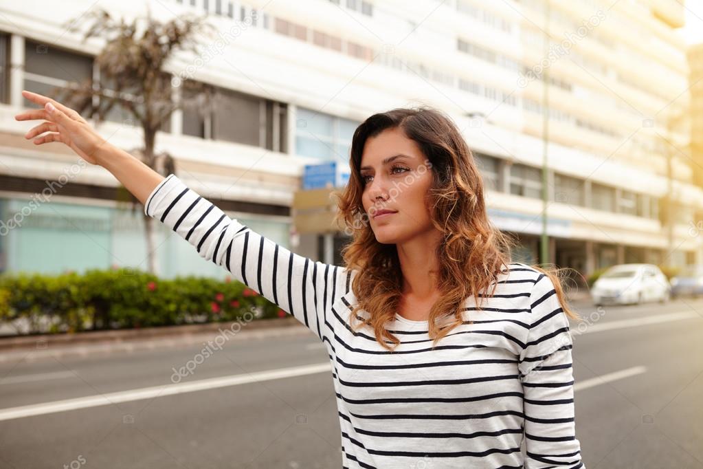 Beautiful woman hailing a cab during the day
