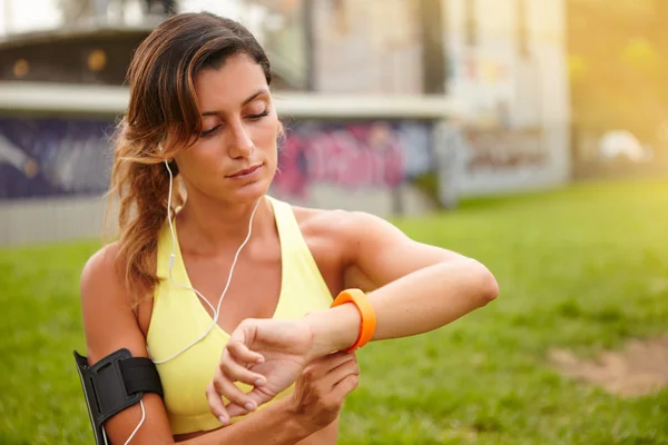 Mujer jogger mirando inteligente pulsera — Foto de Stock