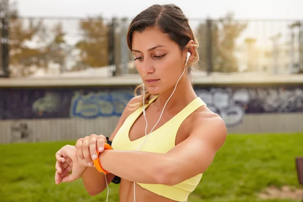 Mujer jogger mirando inteligente pulsera — Foto de Stock