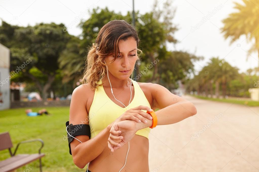 woman jogger looking at smart bracelet