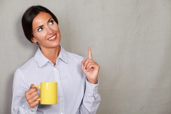 Business lady pointing up and holding cup — Stok fotoğraf