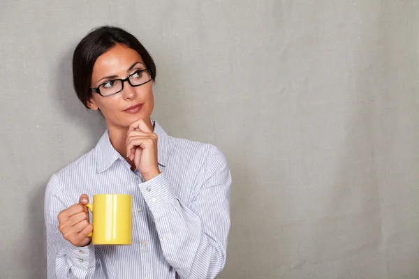 Wondering businesswoman with mug of drink — Stok fotoğraf