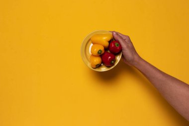 Sarı arka planda küçük kırmızı ve sarı biberli küçük sarı tabak.