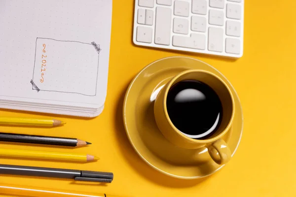 ノートのキーボードとカップは 弾丸ジャーナルを作るためのツールと一緒に黄色の背景にコーヒー — ストック写真