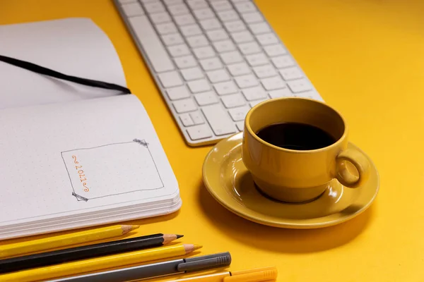 ノートのキーボードとカップは 弾丸ジャーナルを作るためのツールと一緒に黄色の背景にコーヒー — ストック写真