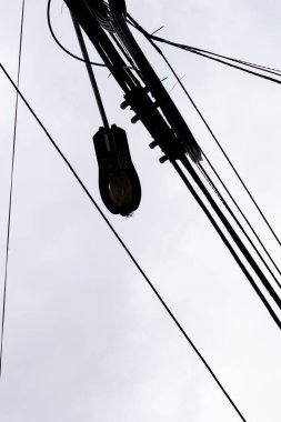 Elektrik kablolarının silueti bulutlu ve gri gökyüzü olan bir şehrin evlerinin ışığı için.