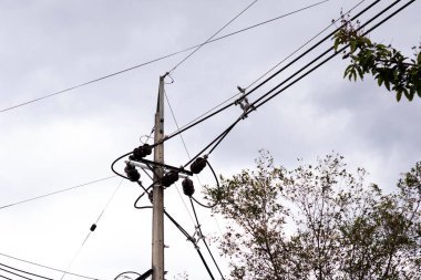 Elektrik kablolarının silueti bulutlu ve gri gökyüzü olan bir şehrin evlerinin ışığı için.