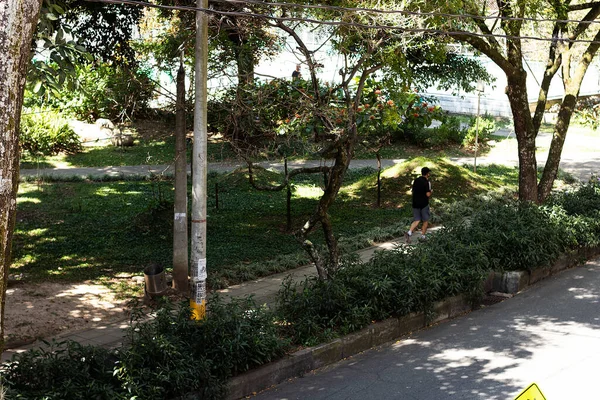 Karantinada parkta koşan bir adam gölgenin altında egzersiz yapıyor.