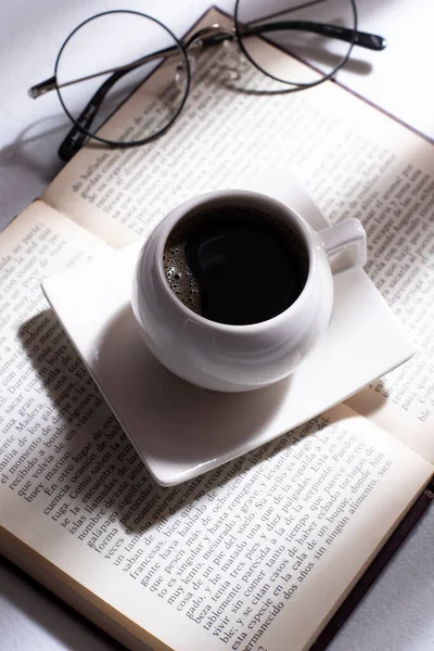 white cup with Colombian coffee on a book and round glasses