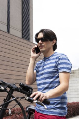 Man talking on cell phone next to his electric bike with worried face