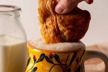 Geleneksel Kolombiya kahvaltısı olarak kahve ve sütle birlikte sarı kupaya batırılmış ekmek.