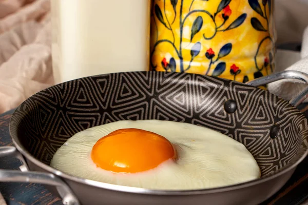 Ortasında sarı sarısı olan kızarmış yumurtalı küçük bir tencere.