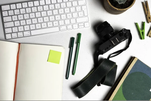 Fotoğraf öğrencisi kalem, defter, kamera ve beyaz bir klavye ile çalışıyor.