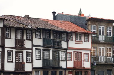 Portekiz 'in Guimaraes kentindeki Largo da Oliveira' da yağmurlu ve bulutlu bir gün, ıslak taş sokaklar ve ortaçağ mimarisi ile tarihi meydanı gösteriyor..                               