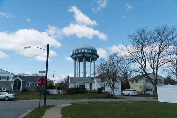 Bethpage, New York, Circa 2020 - Şehir işaretli su kulesi güzel bir günde tipik bir banliyö mahallesinin üzerinde duruyor