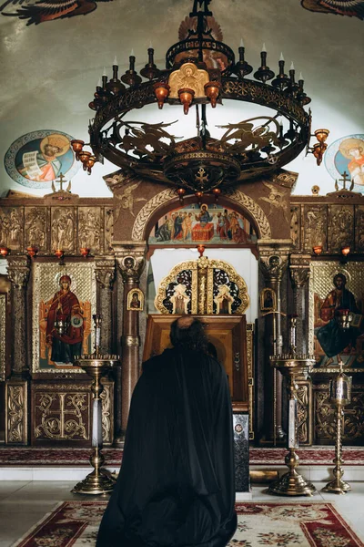 Mnich klečí před ikonou kostela — Stock fotografie