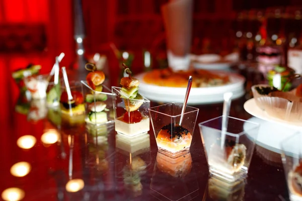 Buffet table with toasts and snacks and desserts in red tones — Stock Photo, Image