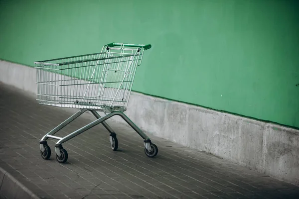Supermarket basket and green wall — Stock Photo, Image