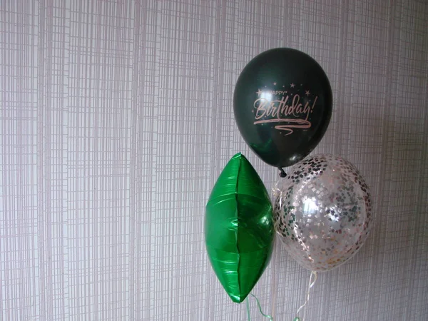 Black balloon with the words HAPPY BIRTHDAY, green balloon and ball with sparkles on a yellow background, place for text