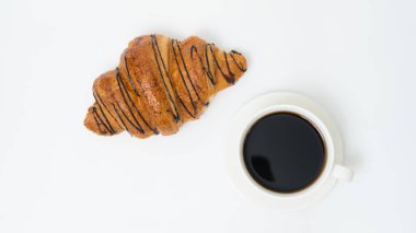Üst ya da düz kahve fincanı ve kruvasanla beyaz arka planda fotokopi alanı. Sabah kahvesi ve atıştırmalık.